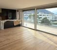 large room, wooden floors, sliding doors, balcony, distant building and mountain view