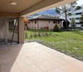 Balcony, paved patio, grass lawn, trees, mountains in the background.