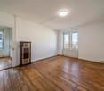 empty room, wooden flooring, two windows, wooden cabinet with radiator