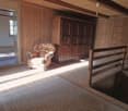 wooden walls, wooden floor, a large wooden wardrobe, a chair with a floral print, sunlight filtering through the window