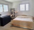 Bedroom with bed, nightstand, lamp, dresser, cat tree, and windows with blinds