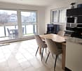 dining room with large windows, balcony, table, chairs, TV, microwave, printer, plant