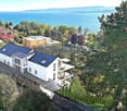 Modern white house with multiple balconies, located on a hill with a view of the sea