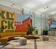Marble flooring, yellow sofa, coffee tables, ottomans, plants, colorful artwork on the wall, reception desk, decorative lamps