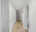 corridor with white doors, tiled floor, ceiling lights