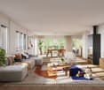 Spacious open-plan living area with large windows, grey sectional sofa, wooden dining table, fireplace, and various decorative elements such as plants and artwork