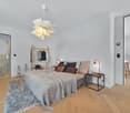 bedroom with double bed, bedside table, lamp, rug, decorative items, clothing rack, potted plant