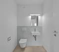 compact bathroom with white walls and flooring, modern design with minimalist white toilet and wall-mounted sink