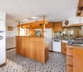 Open kitchen, modern design, black and white checkered tiles, wooden cabinets, center island, white appliances, granite countertops, stainless steel sink, faucet, and storage shelves