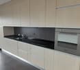 modern kitchen, island countertop, black tiles, wooden cabinets, black counter top, glass balcony, stainless steel oven