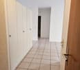 Empty hallway, tiled floor, white wall, white cabinets, wooden door