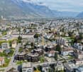 Aerial view of a town with many buildings, mountains in the background, and some in construction