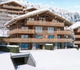 Luxury chalet, wooden exterior, snow-covered roof, multiple balconies, modern design, mountain view
