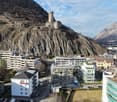 Residential buildings with some in construction, mountainous area with a castle, clear sky