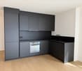 modern kitchen with black cabinets, wooden floor, built-in oven, sink, faucet, power outlet