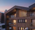 Modern building, wooden exterior, balconies, large glass windows, snow on the ground, snow covered trees