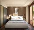 double bed, white headboard, white bedding, nightstands with lamps and potted plants, brick wall, framed art, wooden floor, sliding glass doors, wooden balcony