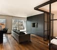 modern apartment with wooden floor, large windows, balcony, couch, dining table, TV, kitchen area