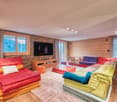 living room with wooden flooring, large sofas, coffee table, TV, stone accent wall, window