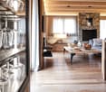 wooden floors, fireplace, couch, coffee table, wall mounted TV, shelves with wine glasses, wooden cupboards
