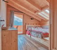 double bed, wooden walls and floor, balcony, wooden storage, white curtains