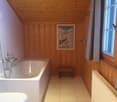 Bathroom with wooden paneled walls, a large bathtub, and a framed artwork on the wall