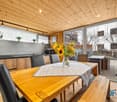 dining area with a wooden table, wooden benches, wooden cabinets, black chairs, gray ceiling with lights, windows, wooden floor