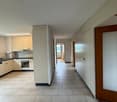 Tiled hallway, kitchen with appliances and cabinets, white walls and ceiling, central heating radiators