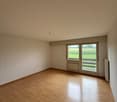 Empty room, wooden floor, large windows, white walls, heater.