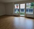 Empty room with wooden floor, large windows and a view of a balcony.