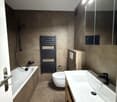Bathroom: bathtub, toilet, sink, tiled walls, towel rack, modern design, large mirror