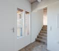 white entrance door, tiled floor, staircase leading to upper floor, glass window with metal railing