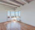 Wooden flooring, white walls, 2 windows, wooden door, balcony, radiator.