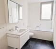 Bathroom with bathtub, toilet, sink, mirror, white tiles, black tiles floor, shower head and faucet