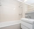 Bathtub, shower, sink, mirror, white tiles, modern fixtures