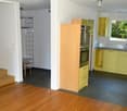 large kitchen with black tiles, yellow cabinets, wooden stove with microwave, sink and faucet, built-in dishwasher, balcony, metal stand for clothes