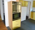 Double oven, yellow cupboards, gray floor, kitchen cabinets