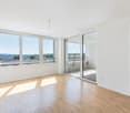 empty room, wooden floors, white walls, large windows, sliding doors to balcony, view to the mountains