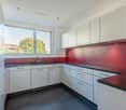 modern kitchen with white cabinets, granite countertop, sink, faucet, red wall, window