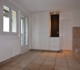 empty room with white cabinet, tiled floor, white doors and windows