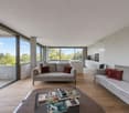 modern living room with large glass windows, 2 couches, round coffee table, wooden floor