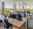 A modern office interior with large windows, offering scenic views of mountains and city.