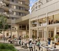 Outdoor dining area with tables and chairs, surrounded by apartment buildings, with a restaurant entrance visible