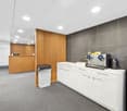Modern office with reception desk, trash bin, white cabinets, and a water dispenser.
