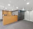 Open space office, wooden counter, reception area, modern design, glass partitions, grey carpet flooring, built-in office furniture, no visible windows, ceiling-mounted lights