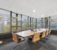 modern office room, large windows, conference table with chairs, equipment, trash can, view of city outside