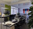 modern office setup, multiple monitors, ergonomic chairs, standing desk, plants, white desk, gray carpet
