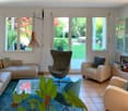 large windows with view on a green garden, modern sofa and armchairs, coffee table, lamps