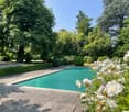 well-manicured garden with lush greenery, neatly trimmed hedges, large swimming pool