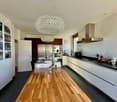 modern kitchen, large wooden table, chandelier, white cabinets, black countertops, stainless steel appliances